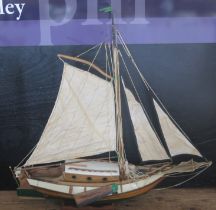 A model of a single masted yacht, the half painted hull of clinker construction, cabin, main sail