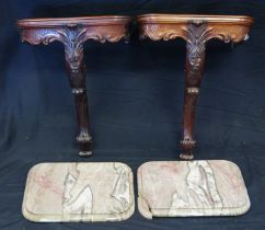 A pair of carved mahogany console tables, with rectangular marble tops, with foliate and scrolled
