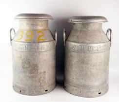 Two aluminium milk churns and covers, with loop carrying handles, 48cm high.
