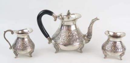 An Indian silver three-piece tea set, of squat ovoid form with chased floral decoration, on swept