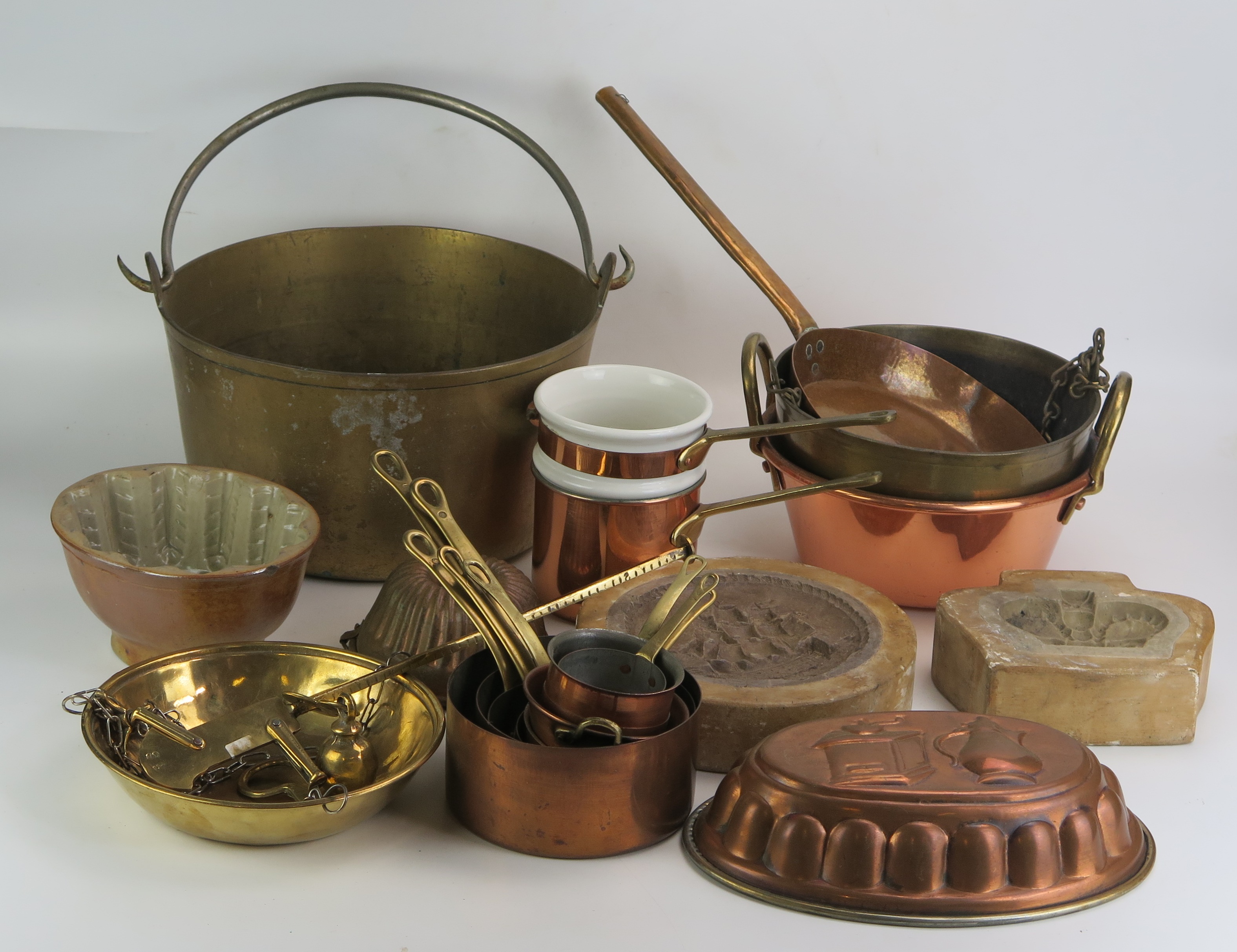 A collection of assorted kitchenalia, includes graduated saucepans, preserve pans, moulds, brass