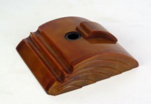 An Art Deco period orange Bakelite ink stand, of arched outline, with sliding top to the inkwell,