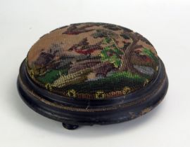 A Victorian circular ebonised foot stool with beadwork stuff-over top of birds amongst trees, raised