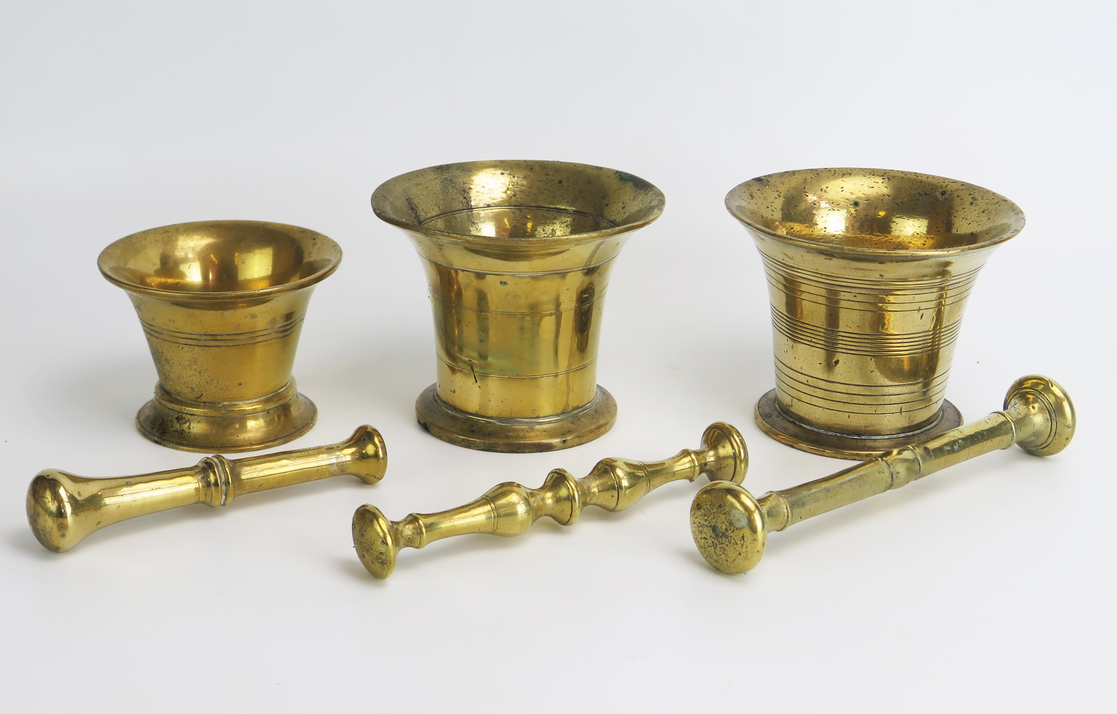 Three 18th century brass pestles and mortars, with ring turned decoration.