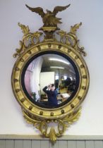 A Regency style gilt wood wall mirror, the circular convex mirror plate within an ebonised slip