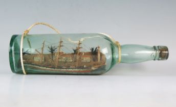 A model of a three-masted ship in a bottle, overall length 31cm.