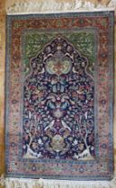 A Persian silk and wool prayer rug, the indigo mihrab with a garden design of animals and birds