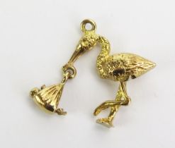 A Precious Yellow Metal Stork and Baby Pendant with articulated legs and holding a babe in swaddling