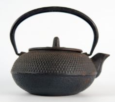 A Japanese iron kettle, of squat circular form with loop swing handle, 15cm long.