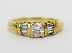 An 18ct Gold and Diamond Ring, the central 5mm stone shouldered by three 2.8mm baguette cut