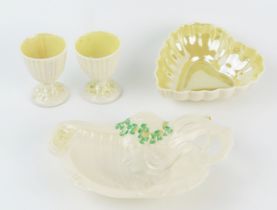 A Belleek porcelain heart-shaped dish, two egg cups and an Art Nouveau influence dish of a maid