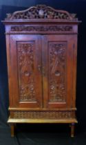 A continental walnut cabinet, with arched and carved foliate and scroll pediment, floral decorated
