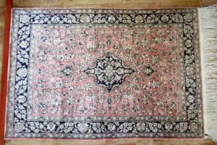 A Persian rug, the main salmon pink field with indigo pole medallion within trailing flowers and