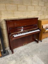 Schimmel (c1991) An upright piano in a traditional bright mahogany case.