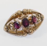 A Victorian hollow gold garnet set brooch, the three oval mixed cut almandine garnets centrally