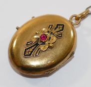 A 19th century French gold oval locket, set with single red stone within inlaid black enamel