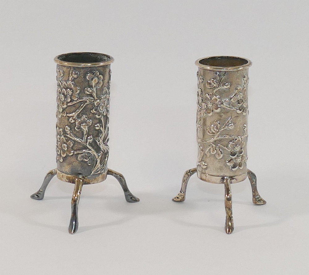 A pair of small Chinese silver cylindrical vases, each raised on three legs and decorated with