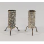 A pair of small Chinese silver cylindrical vases, each raised on three legs and decorated with