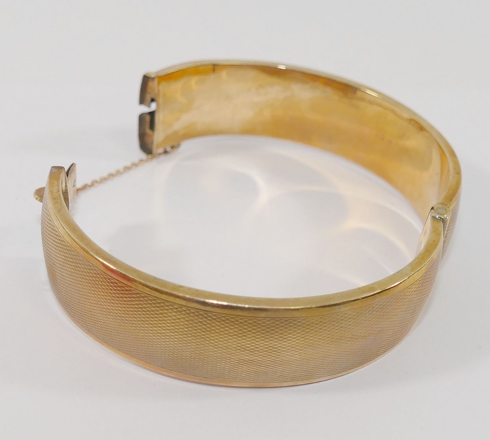 A 9 carat gold hollow hinged sapphire set bangle, with engine turned decoration, the seven round - Image 3 of 3
