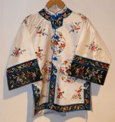 A 20th century Chinese embroidered jacket, the white ground with black borders and blue trim,