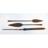 Three African iron spear heads, the longest 50cm, and a carved tribal wooden ceremonial paddle, with