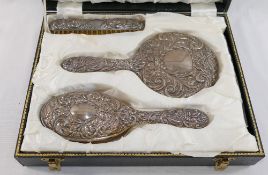 A four piece silver backed dressing table set, comprised of a hand mirror, two brushes and a