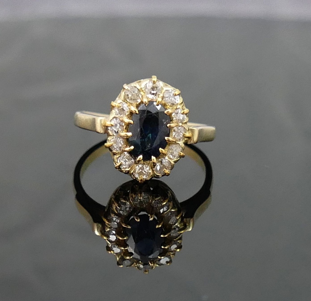 A sapphire and diamond oval cluster ring, the oval mixed-cut sapphire approximately 1 carat,  claw