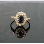 A sapphire and diamond oval cluster ring, the oval mixed-cut sapphire approximately 1 carat,  claw