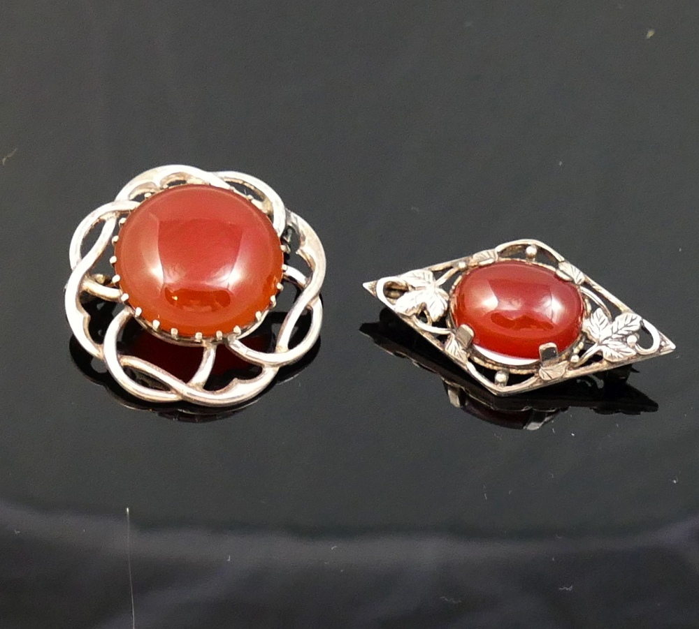A selection of carnelian jewellery comprised of a circular openwork brooch, another brooch, a