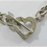 A heavy silver coloured metal necklace with heart and arrow interlocking clasp, stamped 'Tiffany &