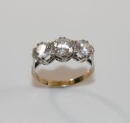 A 9 carat gold diamond simulant three-stone ring, the stones claw-set in white to a yellow shank,