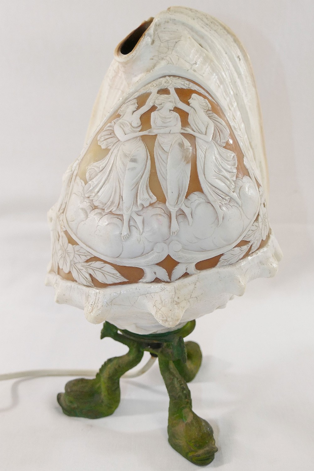 A large Queen helmet conch shell cameo carved with a classical scene of the three graces, mounted to