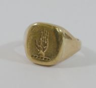 A yellow metal signet ring, intaglio carved with the crest of the palm of a hand, finger size H 1/2,