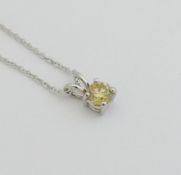 A fancy yellow diamond pendant, the round brilliant cut stone 0.61 carats, VSI clarity, housed in