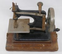 An early 20th century black painted cast iron child's sewing machine entitled ‘Baby’  mounted to a