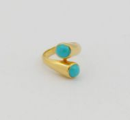A yellow metal cross-over ring, the ends each set with turquoise, stamped '750', finger size J, 7.5g