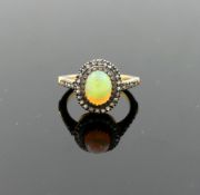 An opal and diamond oval cluster ring, the opal cabochon 1.29 carats, set within rose cut diamond
