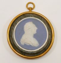 A circular blue and white jasperware medallion depicting the bust of Louis XVI, housed in marble