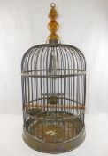 A brass bird cage, with turned wooden surmount, with wooden perch, swing, two feeding bowls and