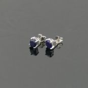 A pair of single stone oval mixed cut treated sapphire stud earrings, the stones 6.5mm x 8mm, housed