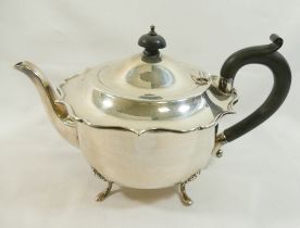 A George V silver teapot, Birmingham 1933, with shaped rim, ebonised knop and handle, raised on four