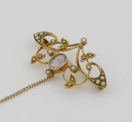 An Edwardian amethyst and seed pearl openwork brooch stamped ‘15ct’ with safety chain, 4.1cm wide,