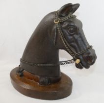 A 20th century cast iron horses head, mounted to an oval oak plinth, with steel chain reins and