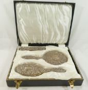 A four piece silver backed dressing table set, comprised of a hand mirror, two brushes and a