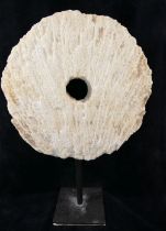 A large coral circular carved disc with central hole, (similar to that of a rai stone), raised on