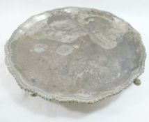 A George V circular silver tray, with shaped and gadrooned rim, raised on four hoof feet, London