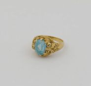 An ornate yellow metal ring, set with single oval mixed-cut synthetic spinel, the shank stamped '