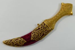 An Indian jambiya dagger, with gilt metal handle and curved steel blade, the red fabric covered