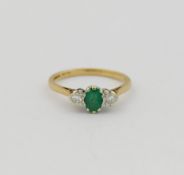 A 9 carat gold emerald and diamond three stone ring, the oval mixed cut emeralds set between two