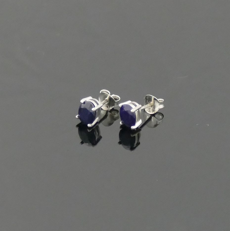 A pair of single stone oval mixed cut treated sapphire stud earrings, the stones 6.5mm x 8mm, housed